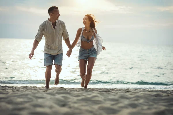 couple walking on empty sandy sea beach in sunset
