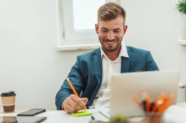 Genç mutlu serbest çalışan, yeni iş projeleri için gündelik ofiste plan yapıyor..