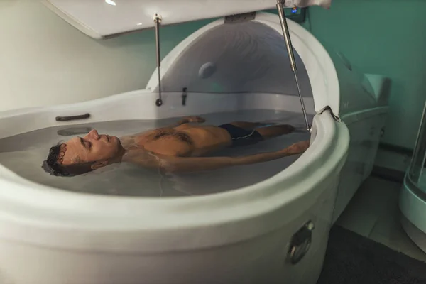 Relaxed man is floating in a sensory deprivation tank. He is very relaxed. Welness and Spa concept.