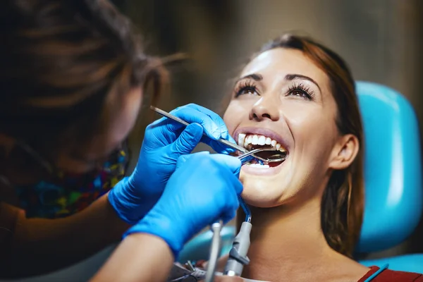 那位年轻貌美的女士正在看牙医 她坐在牙医的椅子上 牙医在她的牙齿上套上牙套 把美观的 自我调整的语言锁放在牙齿上 — 图库照片