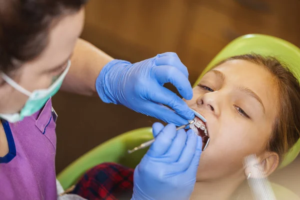 치과에 그녀는 의자에 의사는 그녀의 치아에 교정기를 놓습니다 — 스톡 사진