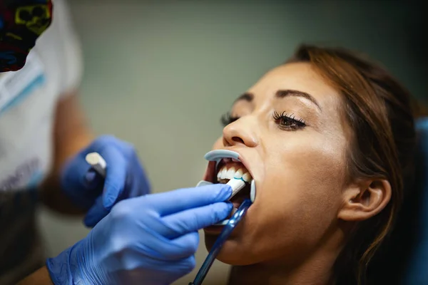 その美しい若い女性は歯医者にいる 歯医者の椅子に座り歯の上に歯を食いしばり — ストック写真