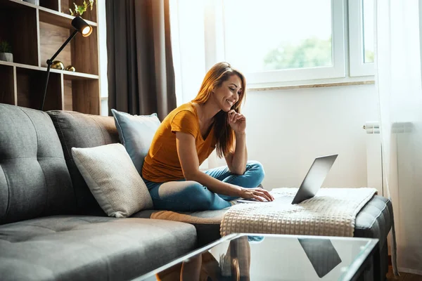 매력적 여자가 소파에 앉아서 노트북을 사용하는 — 스톡 사진