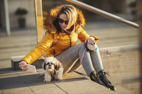 美しい若いファッション女性あります支出時間とともに彼女のかわいいペット犬遊びで街の通り 作りセルフィー — ストック写真