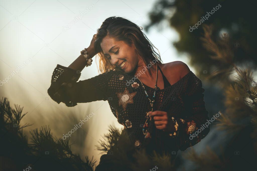 A beautiful young woman is having fun and relaxing on the beach at the sunset. 