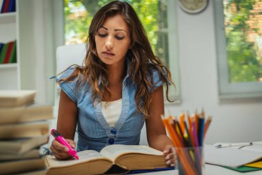 Kitaplı güzel düşünceli genç kız öğrenci okul kütüphanesinde sınav ve öğrenim dersleri hazırlıyor..