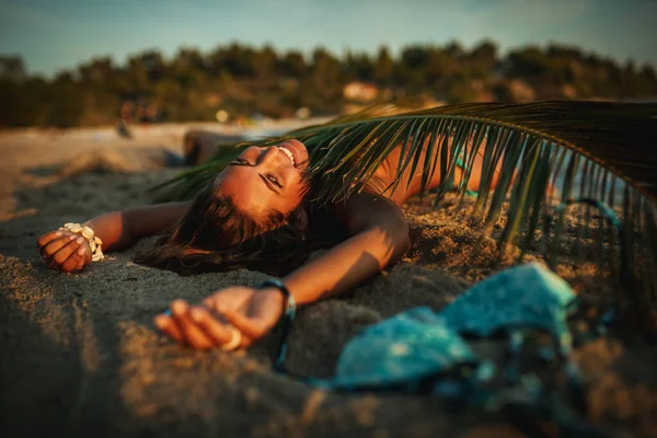 Strzał Atrakcyjnej Młodej Kobiety Leży Tropikalnej Piaszczystej Plaży Pokrytej Liściem — Zdjęcie stockowe