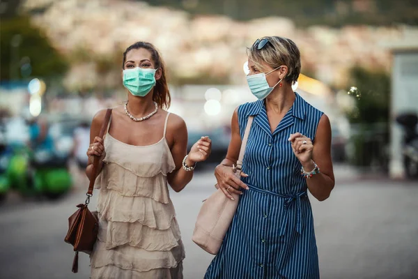 地中海の素晴らしい街を探索しながら外科マスクを身に着けている2人の魅力的な女性の友人のショット — ストック写真