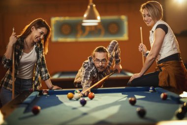 Genç gülümseyen neşeli arkadaşlar işten sonra barda bilardo oynuyorlar. Onlar eğlence aktivitelerine katılırlar..