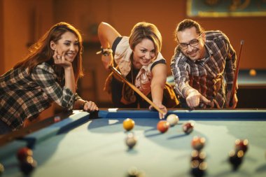 Genç gülümseyen neşeli arkadaşlar işten sonra barda bilardo oynuyorlar. Onlar eğlence aktivitelerine katılırlar..