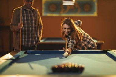 Genç gülümseyen neşeli kadın işten sonra barda bilardo oynuyor. Eğlence aktivitelerine katılıyor..