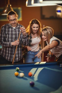 Genç gülümseyen neşeli arkadaşlar işten sonra barda bilardo oynuyorlar. Onlar eğlence aktivitelerine katılırlar..