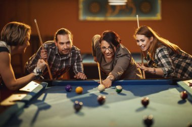 Genç gülümseyen neşeli arkadaşlar işten sonra barda bilardo oynuyorlar. Onlar eğlence aktivitelerine katılırlar..