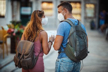 Koruyucu N95 maskeli mutlu bir çiftin Corona 'da tatil yaparken ve bir Akdeniz şehrini keşfederken çekilmesi.. 