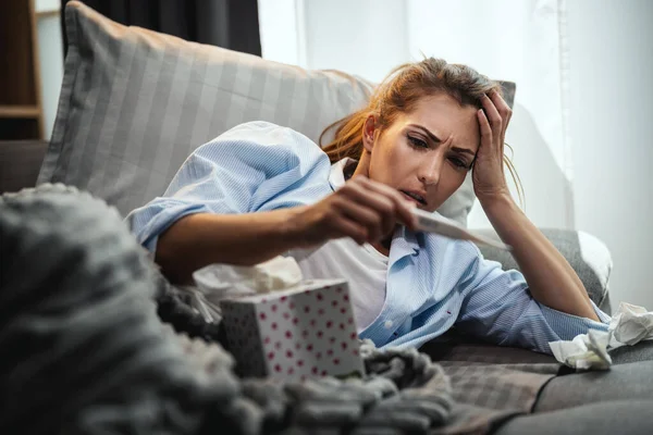 Fiatal Fekszik Beteg Otthon Kanapén Nézi Hőmérő — Stock Fotó