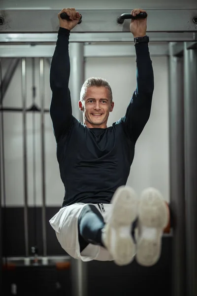 ジムでの筋力トレーニングのトレーニング中に座位の練習を行うことに焦点を当てたスポーツウェアの筋肉若い男 — ストック写真