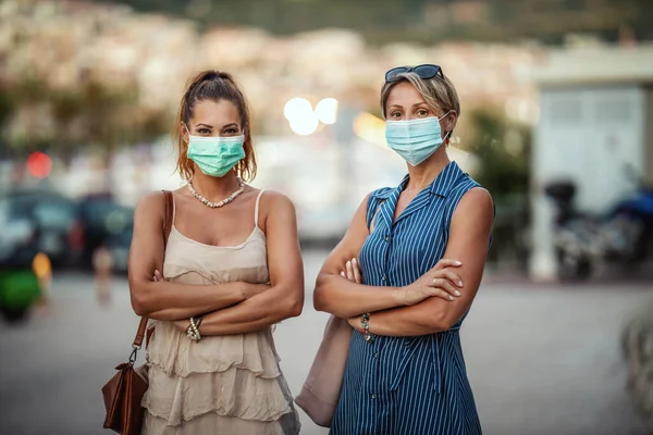 地中海の素晴らしい街を探索しながら外科マスクを身に着けている2人の魅力的な女性の友人の肖像画 — ストック写真