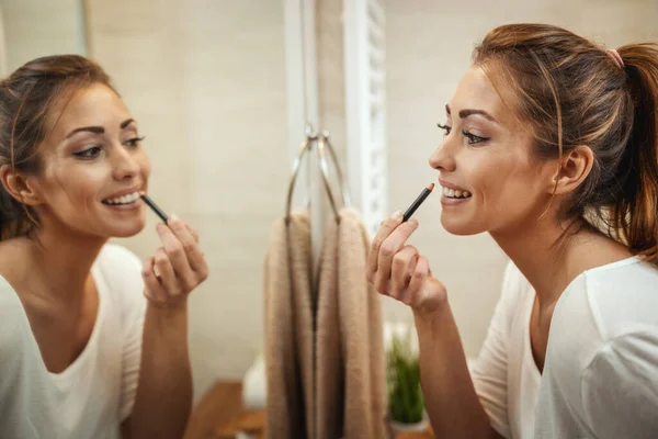 화장실 거울에 립스틱을 매력적 여자의 — 스톡 사진