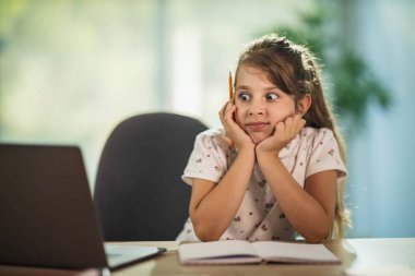 Endişeli küçük bir kızın dizüstü bilgisayar kullanması ve COVID-19 salgını sırasında evde online ders almasıyla ilgili sorun yaşaması..
