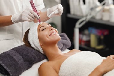 Shot of a beautiful young woman on a facial dermapen micro-needling treatment at the beauty salon. clipart