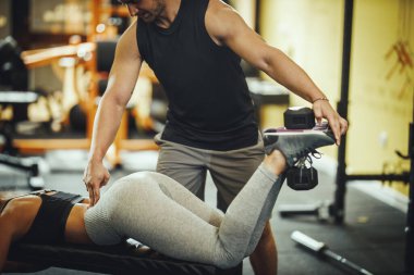 Çekici bir genç kadının spor salonunda kişisel antrenörüyle çalışırken çekilmiş bir fotoğrafı..