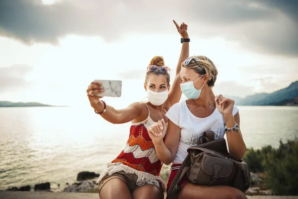 地中海の素晴らしい街を探索しながら 保護マスクを着用し スマートフォンで自撮り魅力的な女性の友人のショット — ストック写真