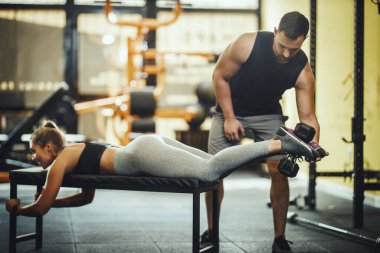 Çekici bir genç kadının spor salonunda kişisel antrenörle çalışması..
