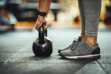 Tanınmayan bir bayan sporcunun spor salonunda kettlebell ile antrenman yaparken kesilen fotoğrafı..