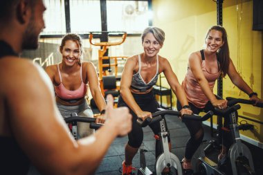Spor salonunda spor bisikleti eğitimi alan üç formda bayan arkadaş grubu..