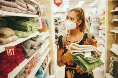 Covid-19 salgını sırasında süpermarketten havlu alırken N95 koruyucu maske takan genç bir kadının fotoğrafı..