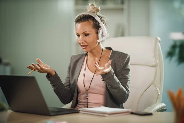 Zdjęcie Atrakcyjnej Młodej Bizneswoman Siedzącej Samotnie Swoim Biurze Słuchawkami Pracującej — Zdjęcie stockowe