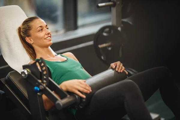 一个穿着运动服在健身房锻炼的肌肉发达的年轻女子中枪 她在髋部信托机上做仰卧起坐练习 — 图库照片
