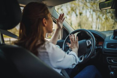 Stresli bir iş kadınının araba sürerken kornaya basması..