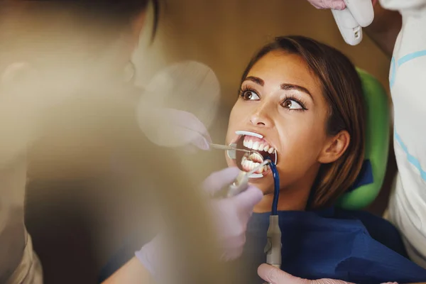 아름다운 여성이 치과에 있습니다 그녀는 의사의 의자에 의사는 그녀의 치아에 — 스톡 사진
