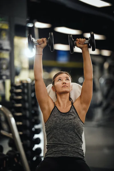 体育館でのハードトレーニングで働くスポーツウェアを着た筋肉質の若い女性のショット 彼女は体重で彼女の肩の筋肉を汲み上げている — ストック写真