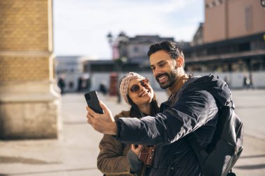 Mutlu, gülümseyen bir turist çifti. Yeni şehirde telefonla selfie çekiyor. Güneşli bir gün.. 