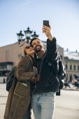 Mutlu, gülümseyen bir turist çifti. Yeni şehirde telefonla selfie çekiyor. Güneşli bir gün.. 