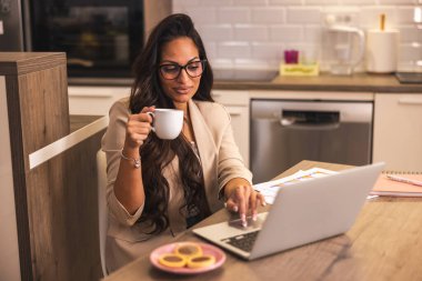 Genç iş kadını evde kahve içerken işini yapıyor.. 