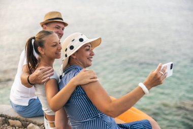 Mother pointing at sea with her finger and father and daughter looking at it while enjoying summer day. 