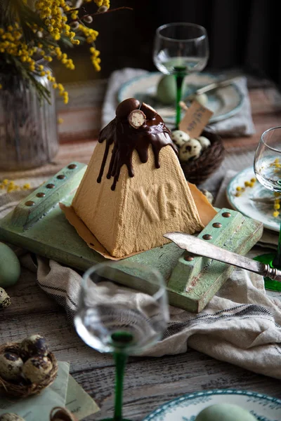 Orthodox Easter table setting with caramel easter cottage cheese cake on wooden light green board on grey wooden table