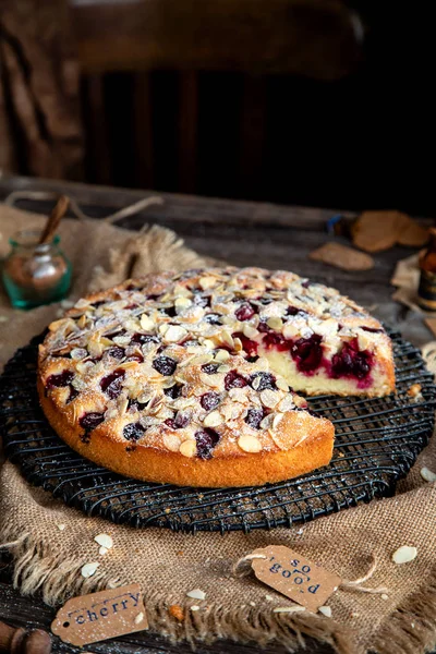 homemade tasty biscuit cake with cherries, almond flakes, powdered sugar on top