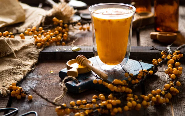 hot drink with sea buckthorn berries and honey in tall glass