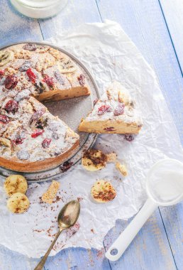 Fındık, susam ve kızılcık mavi ahşap bir masa üzerinde bir dilimlenmiş muz pasta.