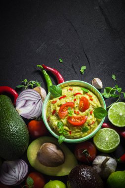 Arka plan ile guacamole ve malzemeler: domates, biber biber, kireç, soğan, sarımsak, dereotu ve kekik