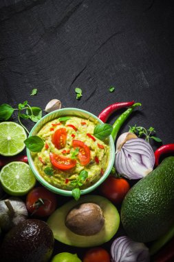 Arka plan ile guacamole ve malzemeler: domates, biber biber, kireç, soğan, sarımsak, dereotu ve kekik