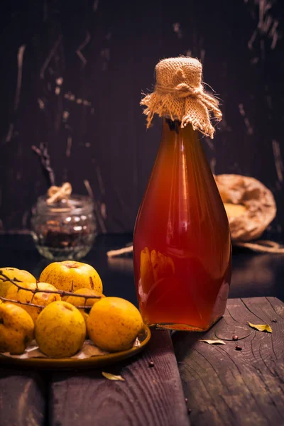 Bottle liquor wooden table ingredients tincture fruit quince — Stock Photo, Image