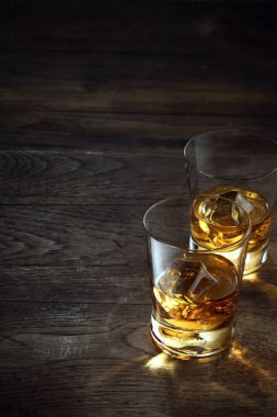 close up view of  two glasses with ice and whiskey on wooden background clipart