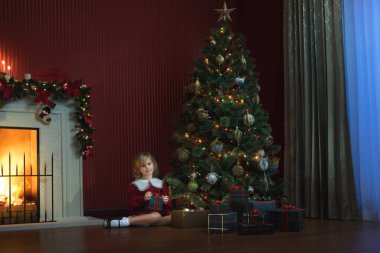 portrait of little girl is waiting for Santa coming in domestic environment clipart