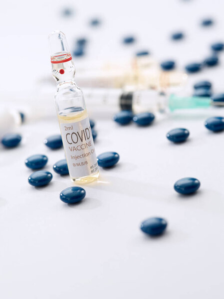 Крупный план ампулы с лекарствами, таблетками и шприцем на белой спине 