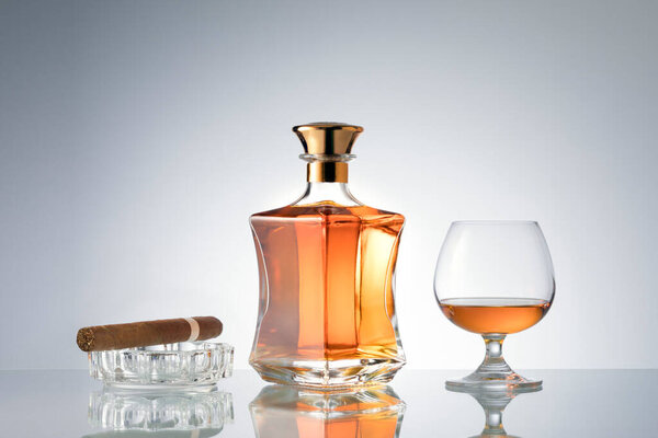 закрытый вид на сигару, бутылку коньяка и стакан в сторону на серой спине. 